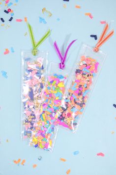 two plastic bags filled with confetti and sprinkles on a blue surface