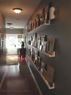 a long hallway with pictures on the wall and framed photos on the shelves above it