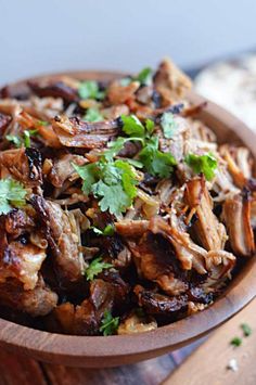 a wooden bowl filled with meat and cilantro