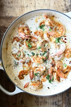 a pan filled with shrimp and sauce on top of a wooden table