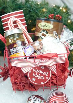 a red basket filled with food next to a christmas tree