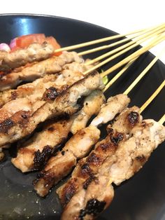 several skewers of meat and vegetables on a black plate