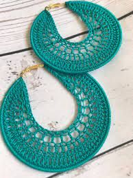 a pair of green crocheted hoop earrings on top of a white wooden table