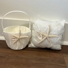 two white baskets sitting on top of a wooden floor next to a bag and pillow