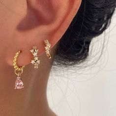 a close up of a person wearing ear rings with pink and white stones on them