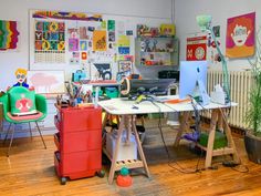 an office with lots of clutter and art work on the walls, desks and chairs