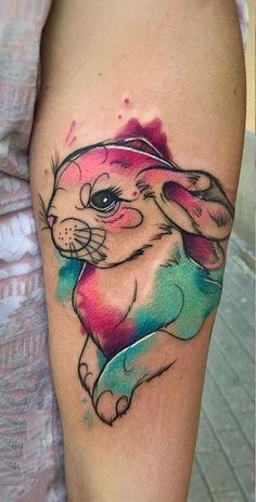 a colorful rabbit tattoo on the left thigh and right leg, with watercolor splashs