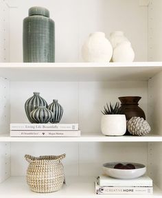 three shelves with vases, books and other decorative items on top of each shelf