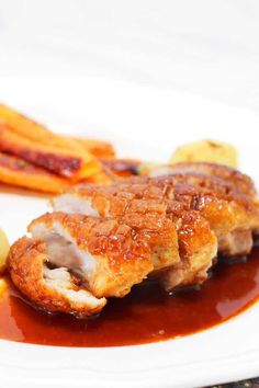 some food is on a white plate with sauce and french fries in the foreground