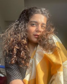 a woman with long curly hair wearing a yellow and white scarf