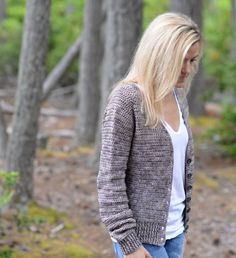 a blonde woman standing in the woods with her hand on her hip and looking down