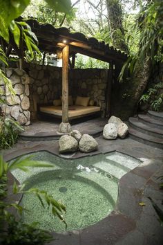 an outdoor hot tub surrounded by rocks and greenery