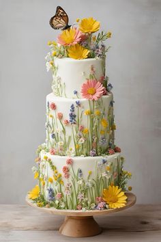 a three tiered cake with flowers and a butterfly sitting on top of the cake