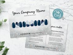 two business cards with blue and white nail polishes on them next to some green leaves