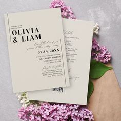 two wedding cards on top of purple flowers