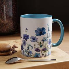 a blue and white coffee mug sitting on top of a wooden table next to a spoon