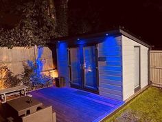 a small backyard shed with blue lights on the roof and deck area next to it