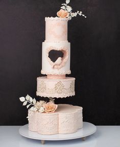 a three tiered cake with flowers and hearts on the top is decorated in pink