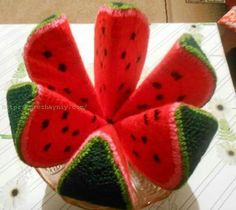 a knitted watermelon flower sits in a glass vase on a table top