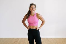 a woman in pink top and black leggings standing with her hands on hips