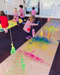 children are playing with colored sand on the ground