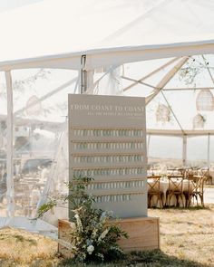 a sign that says from coast to coast sits in the grass near tables and chairs