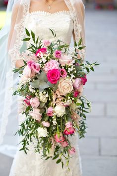 a bride holding a bouquet of pink and white flowers