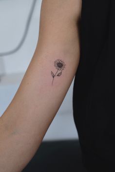 a woman's arm with a single flower tattoo on the left side of her arm