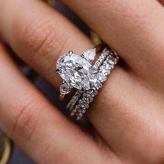 a woman's hand with a diamond ring on it and two wedding bands around her wrist