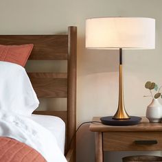 a lamp on a nightstand next to a bed