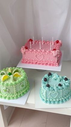 three cakes with candles on them sitting on top of a white table next to each other