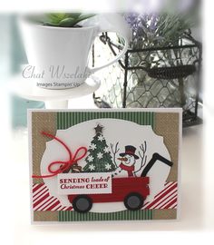 a christmas card with a snowman driving a truck and a tree on the front