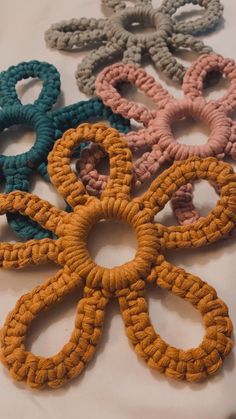 several different colored crocheted hair ties laid out on a white tablecloth with one knot in the middle