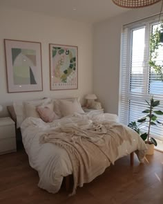 a bed sitting in a bedroom next to a window covered in blankets and throw pillows