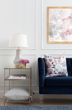 a living room with a blue couch and pink flowers on the table next to it