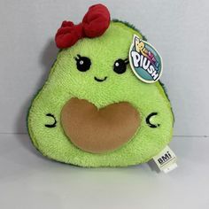 a green stuffed animal with a red bow on it's head and tongue sticking out