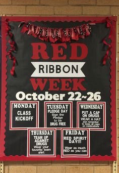 a red ribbon week sign hanging on the side of a wall in front of a brick wall