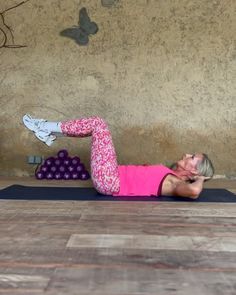 a woman in pink shirt and leggings doing a yoga pose on the floor