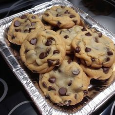 chocolate chip cookies sitting on top of a metal tray in front of an electric stove