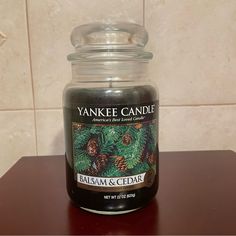 a candle is sitting on a table in front of a tile wall with pine cones