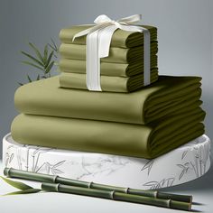 a stack of folded sheets with a white bow on top and bamboo sticks in the background