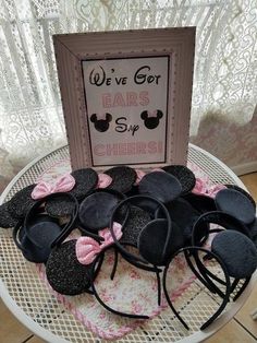 a table topped with lots of black and pink hair accessories next to a sign that says we've got ears for sisters