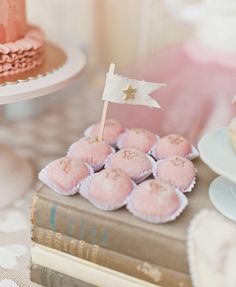 a table topped with cakes and cupcakes covered in frosting next to a flag