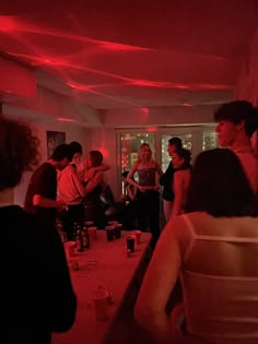 a group of people standing in a room with red lights on the ceiling and walls