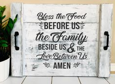 a white wooden sign with the words, be the food before us and the family beside it is love between us and amen