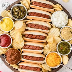 a platter filled with hot dogs, chips and condiments