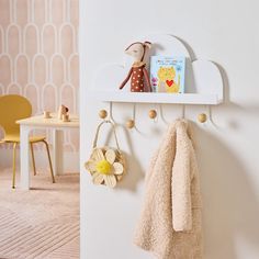 a child's room with a teddy bear, book shelf and coat rack on the wall