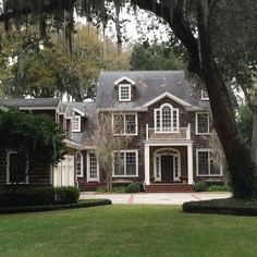 a large brown house surrounded by lush green trees