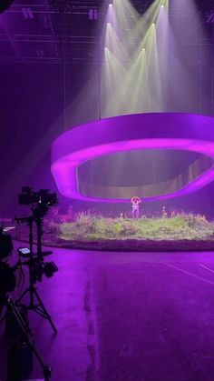 the stage is lit up with purple lighting and green grass in front of two spotlights