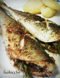 two fish are sitting on a plate with some potatoes and rosemary garnishes